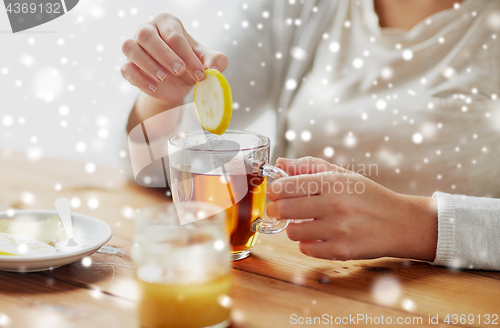 Image of close up of woman adding honey to tea with lemon
