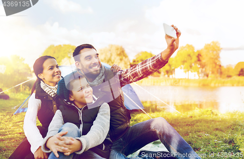 Image of family with smartphone taking selfie at campsite