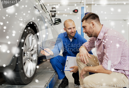 Image of auto mechanic with clipboard and man at car shop