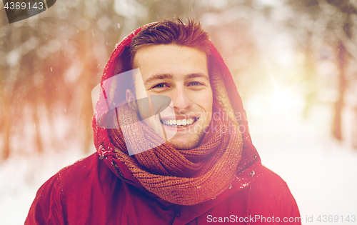 Image of happy man in winter jacket with hood outdoors