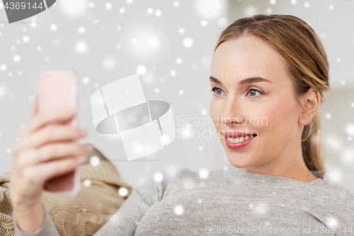 Image of happy woman taking selfie with smartphone at home