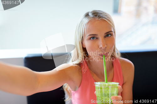 Image of woman with smoothie taking selfie at restaurant