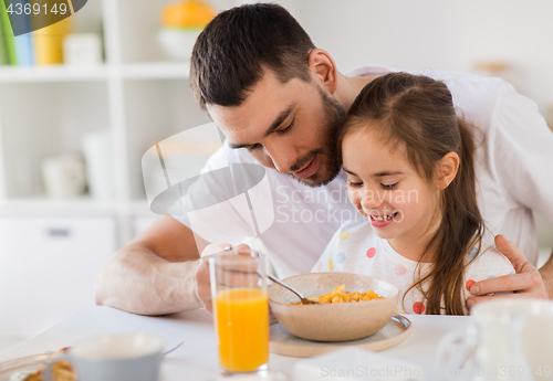 Image of happy family eating flakes for breakfast at home