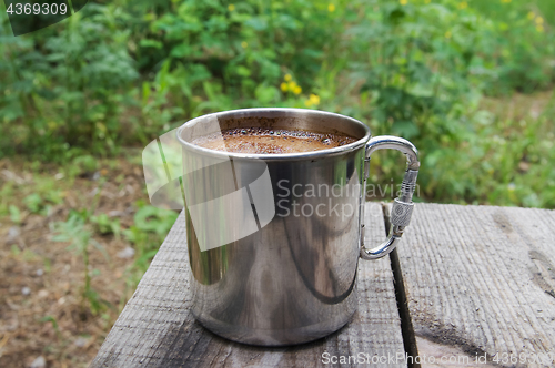 Image of Metal mug of coffee on wooden table