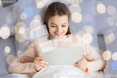 Image of happy girl in bed with tablet pc over lights