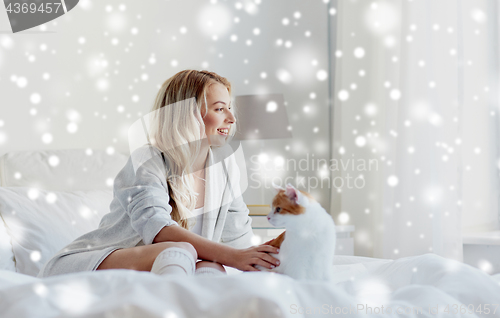 Image of happy young woman with cat in bed at home