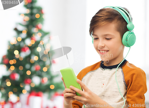 Image of boy with smartphone and headphones at christmas