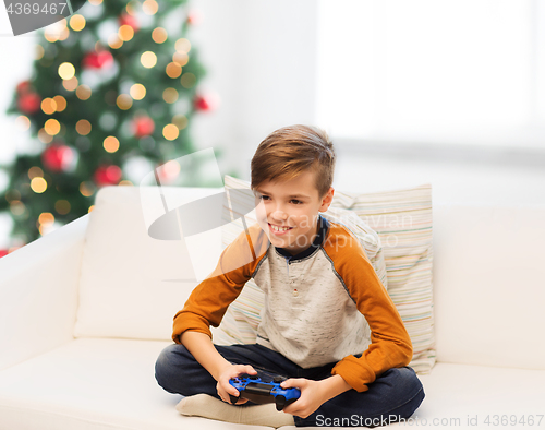 Image of boy with gamepad playing video game at christmas