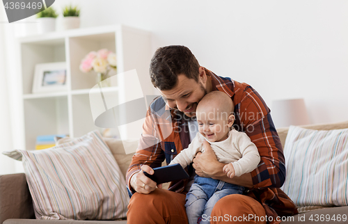 Image of father and baby boy with smartphone at home