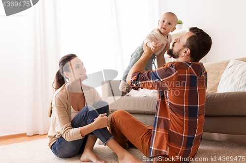 Image of happy mother and father playing with baby at home