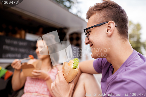 Image of happy man eating hamburger at food truck