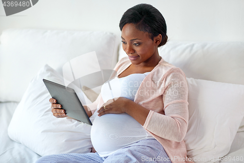 Image of happy pregnant woman with tablet pc at home