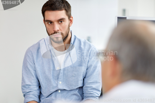 Image of young male patient talking to doctor at hospital