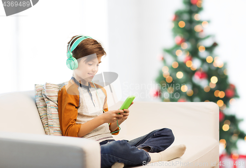 Image of boy with smartphone and headphones at christmas