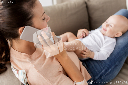 Image of mother with baby calling on smartphone at home