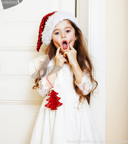 Image of little cute girl in santas red hat waiting for Christmas gifts. 