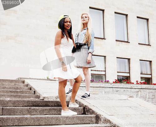 Image of Two teenage girls infront of university building smiling, having