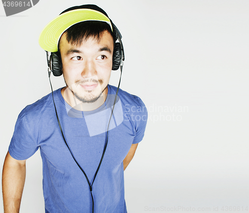 Image of young asian man in hat and headphones listening music on white b