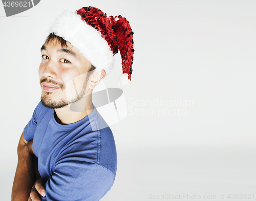 Image of funy exotical asian Santa claus in new years red hat smiling