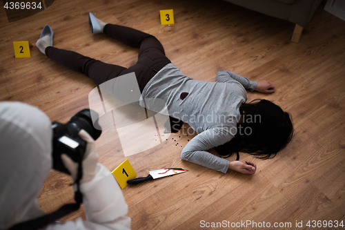 Image of criminalist photographing dead body at crime scene