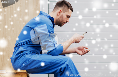 Image of auto mechanic smoking cigarette at car workshop