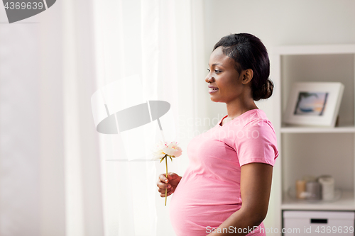 Image of happy african american pregnant woman with flower