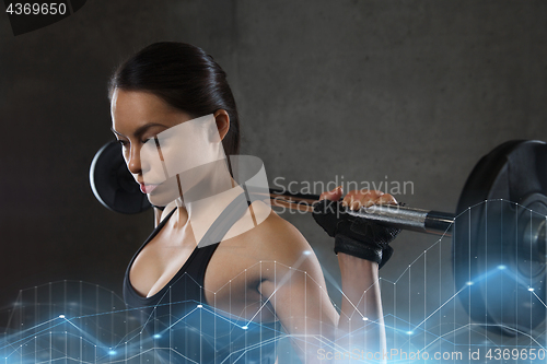 Image of young woman flexing muscles with barbell in gym