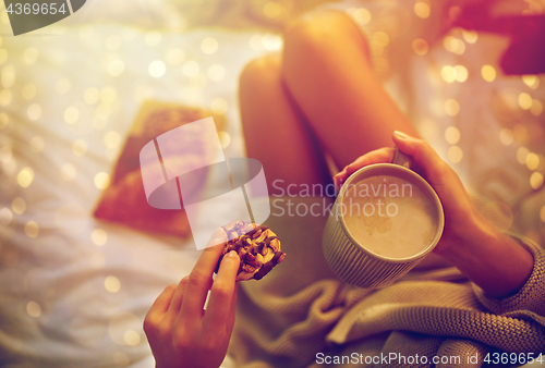 Image of close up of woman with cocoa cup and cookie in bed