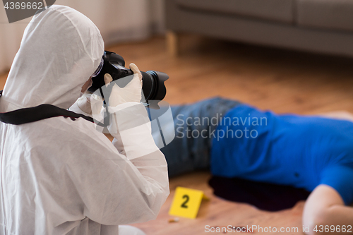 Image of criminalist photographing dead body at crime scene