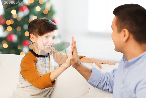 Image of happy father and son doing high five at christmas