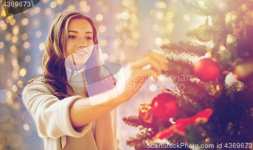 Image of happy young woman decorating christmas tree