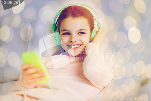 Image of girl with headphones listening to music in bed