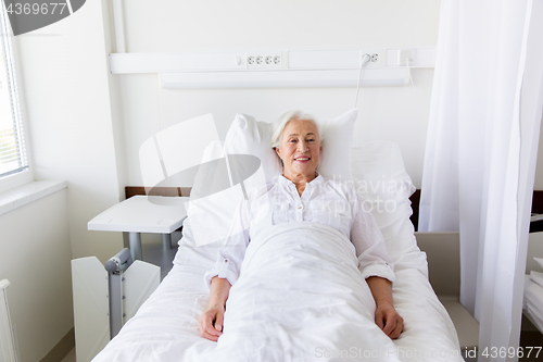 Image of smiling senior woman lying on bed at hospital ward