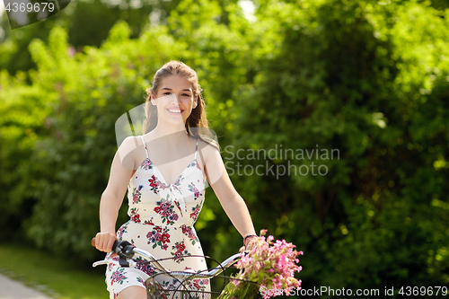 Image of happy woman riding fixie bicycle in summer park