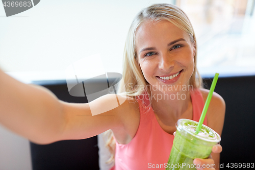 Image of woman with smoothie taking selfie at restaurant