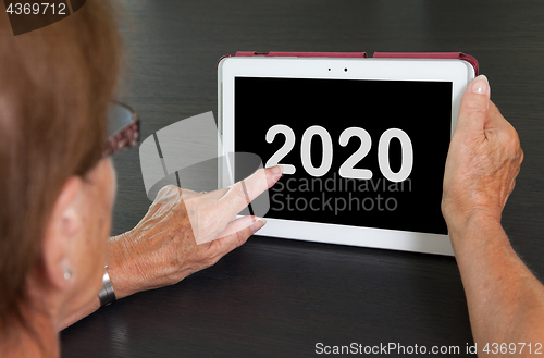 Image of Senior lady relaxing and her tablet - 2020