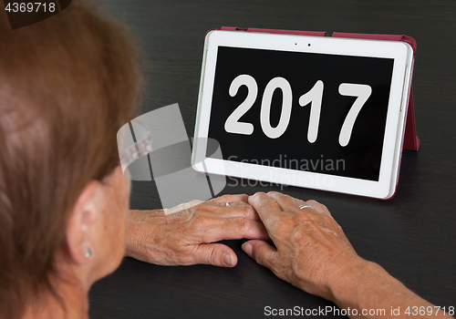 Image of Senior lady relaxing and her tablet - 2017