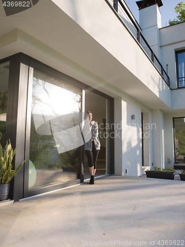Image of woman drinking coffee in front of her luxury home villa