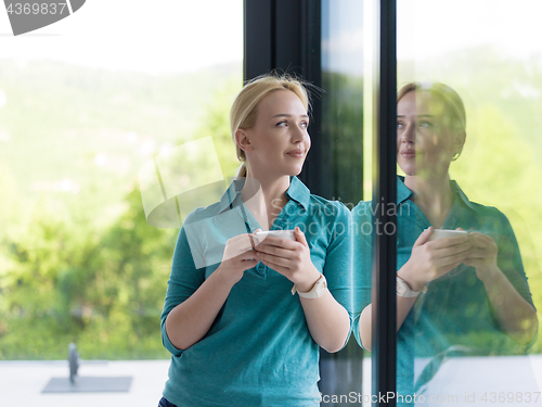 Image of young woman drinking morning coffee by the window