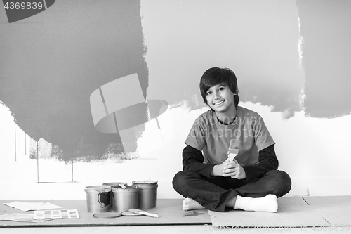 Image of young boy painter resting after painting the wall