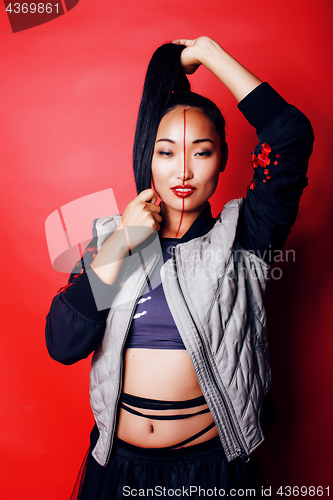 Image of young pretty asian girl posing cheerful on red background, fashion style makeup and hair, lifestyle modern orient people concept