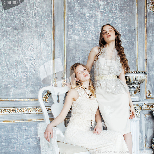Image of two pretty twin sister blond curly hairstyle girl in luxury house interior together, rich young people concept 