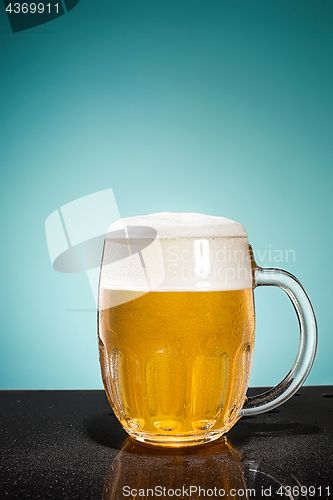 Image of glass of cold frothy lager beer on an old wooden table