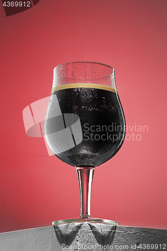 Image of glass of cold frothy dark beer on an old wooden table