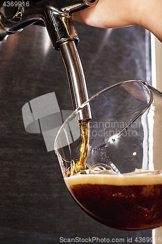 Image of Hand of bartender pouring a large lager beer in tap.