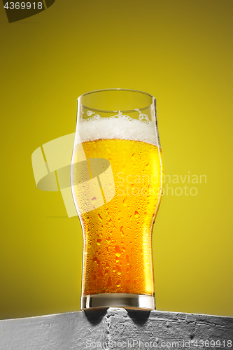 Image of glass of cold frothy lager beer on an old wooden table