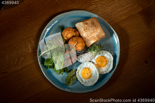 Image of Scrambled eggs on meat with fried potatoes and toast