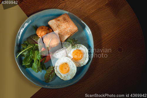 Image of Scrambled eggs on meat with fried potatoes and toast