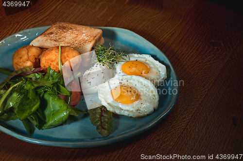 Image of Scrambled eggs on meat with fried potatoes and toast