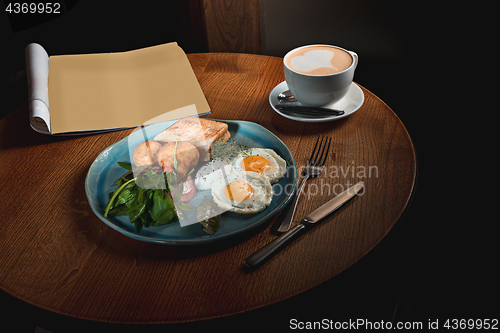 Image of Scrambled eggs on meat with fried potatoes and toast
